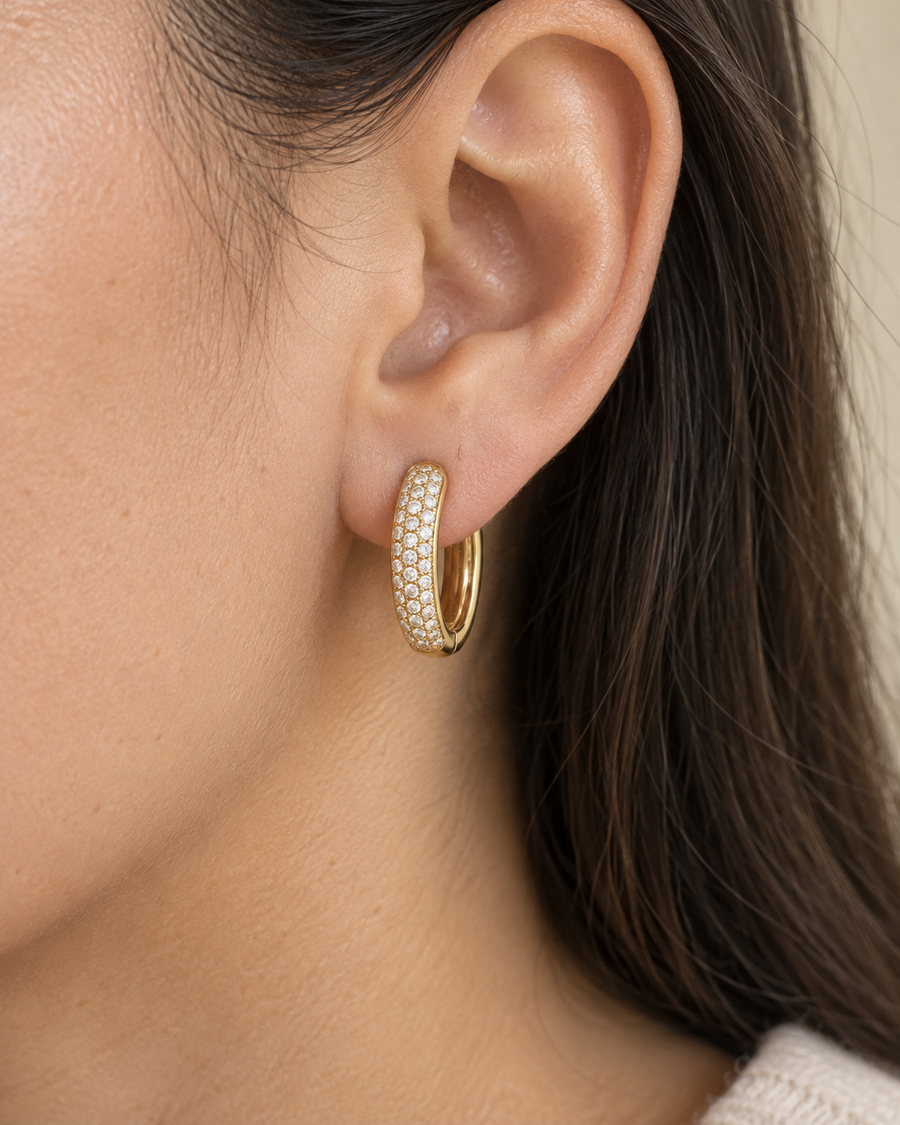 AI-generated visualization — a yellow-gold Pavé Huggie Hoop worn on an adult ear.