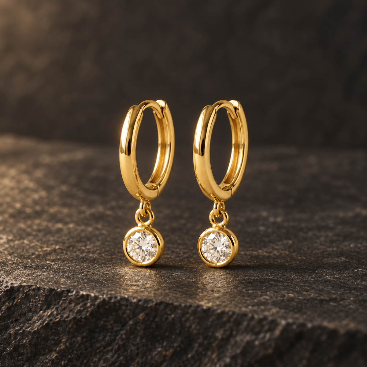AI-generated visualization — yellow-gold Bezel Drop Huggies displayed on dark graphite stone.