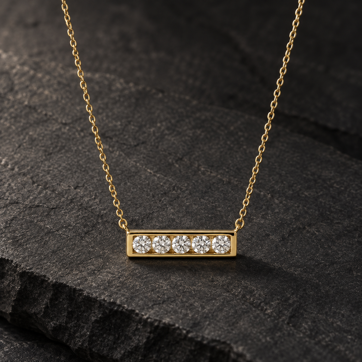 AI-generated visualization — Lab Diamond Five-Stone Bar Necklace in yellow gold on dark graphite stone.