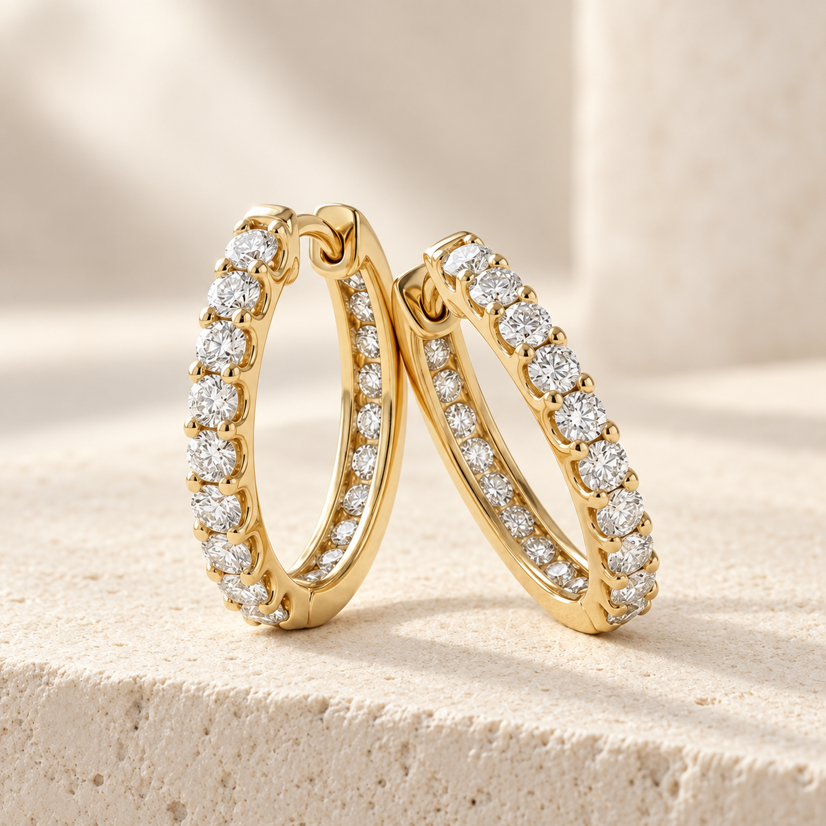 AI-generated visualization — yellow-gold Inside-Out Huggie Hoops with round diamonds on an ivory studio display.