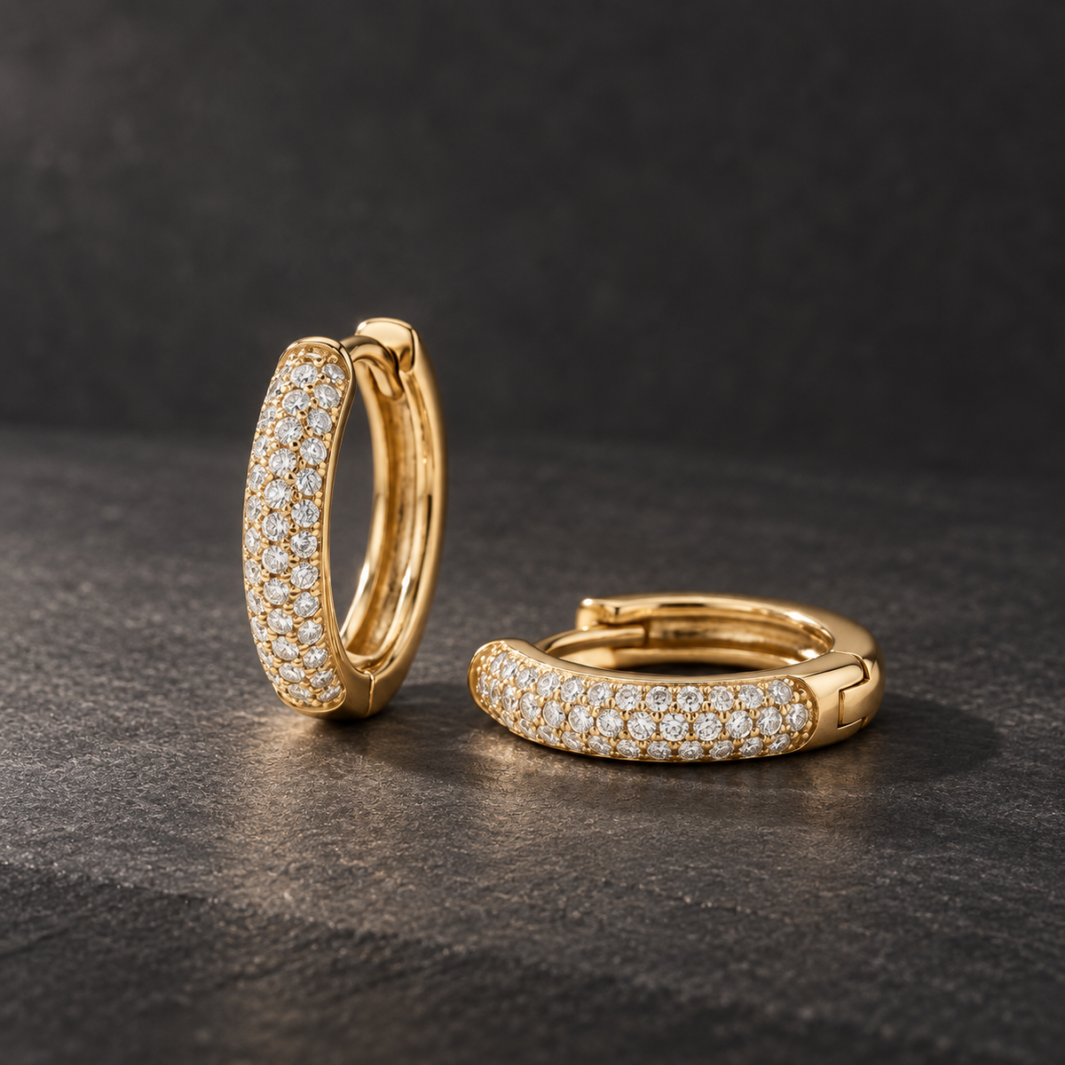 AI-generated visualization — yellow-gold Pavé Huggie Hoops with three staggered diamond rows on dark graphite.